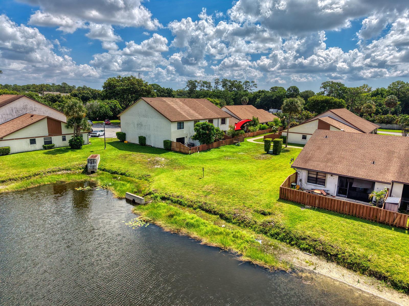 An aerial view shows several residential townhomes with brown roofs situated near a small pond — 1030 Parkside Green Drive # A, FL 33415, FL