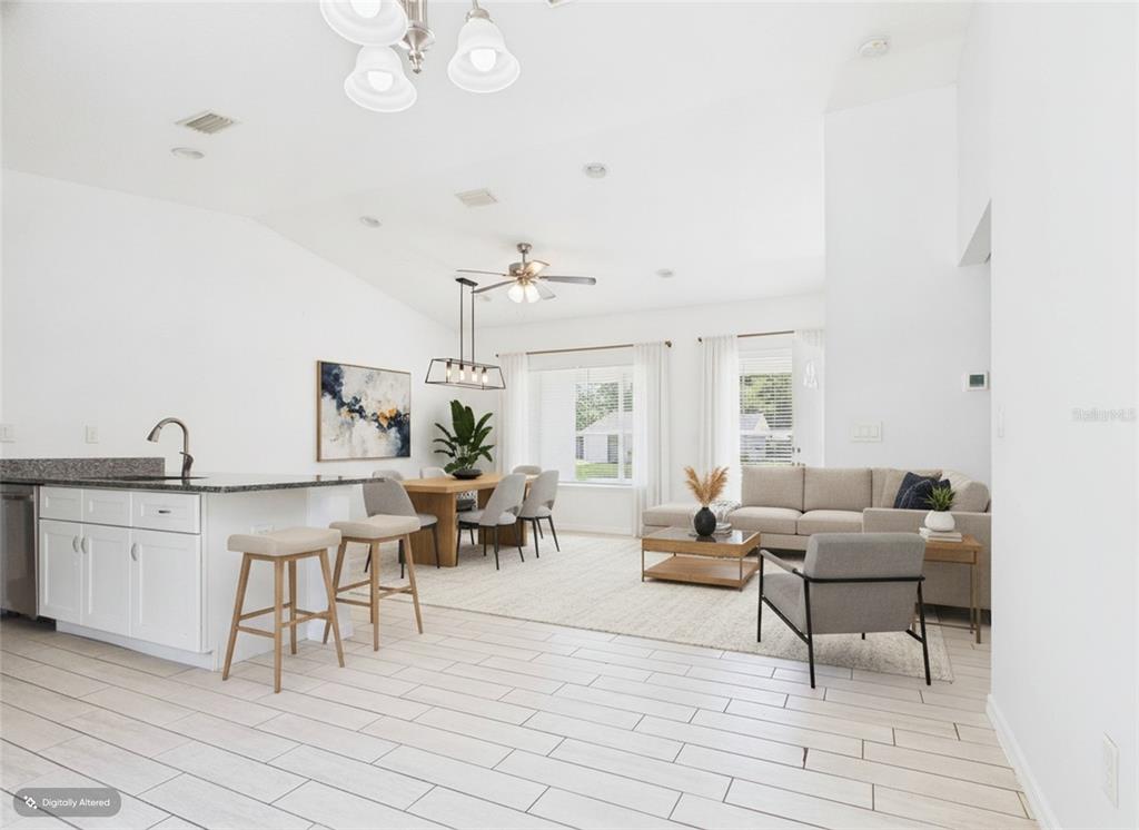 An open-concept living and dining area features white cabinetry, light tile flooring, and neutral furniture — 4309 SW 143RD LANE ROAD, OCALA, FL