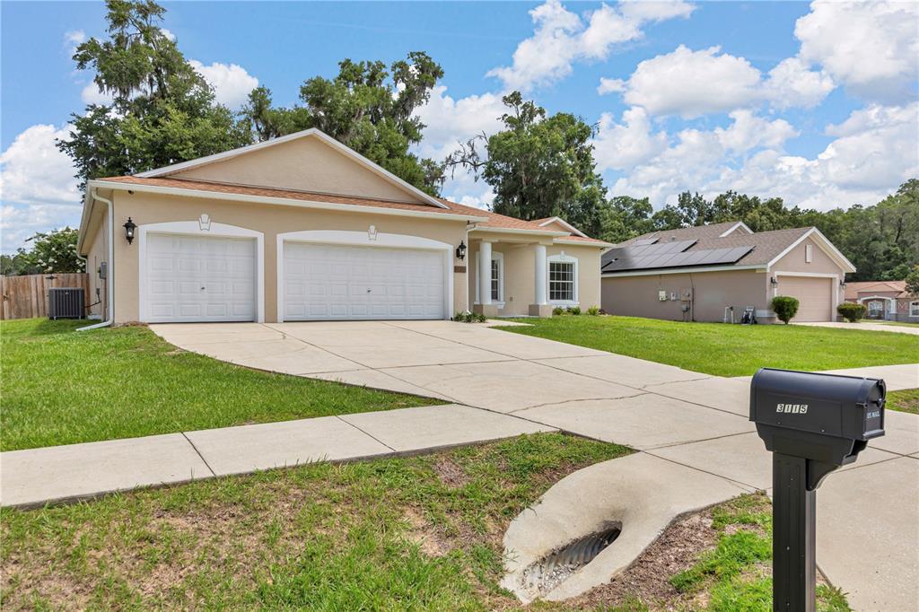 A single-story suburban house with a three-car garage and a concrete driveway — 3115 NE 25TH STREET, OCALA, FL