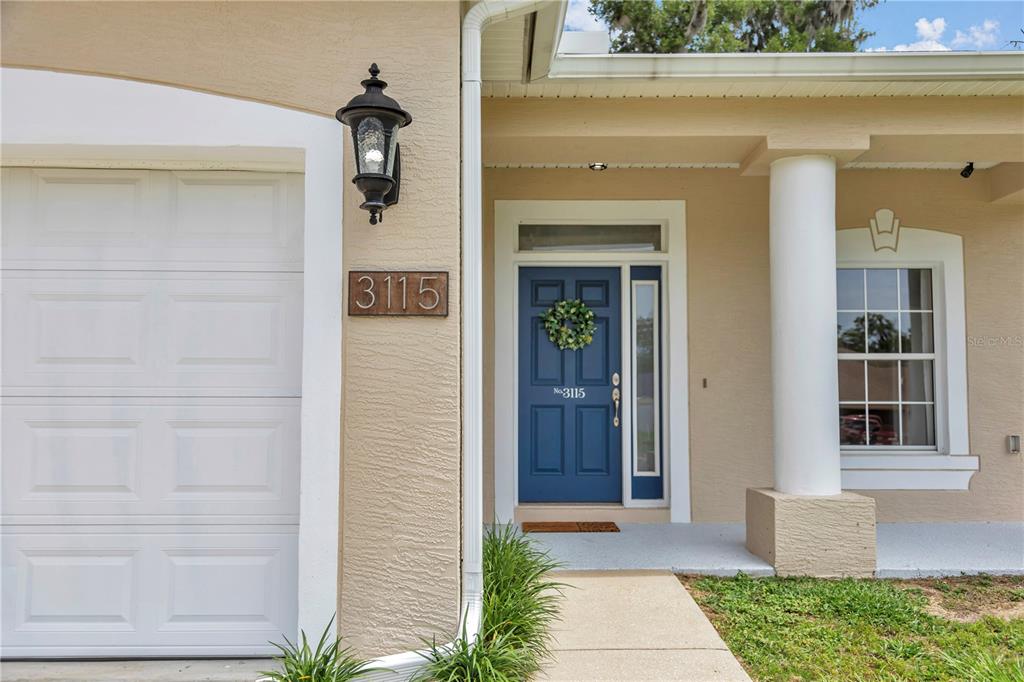 The exterior of a house features a blue front door, a garage, and a column — 3115 NE 25TH STREET, OCALA, FL