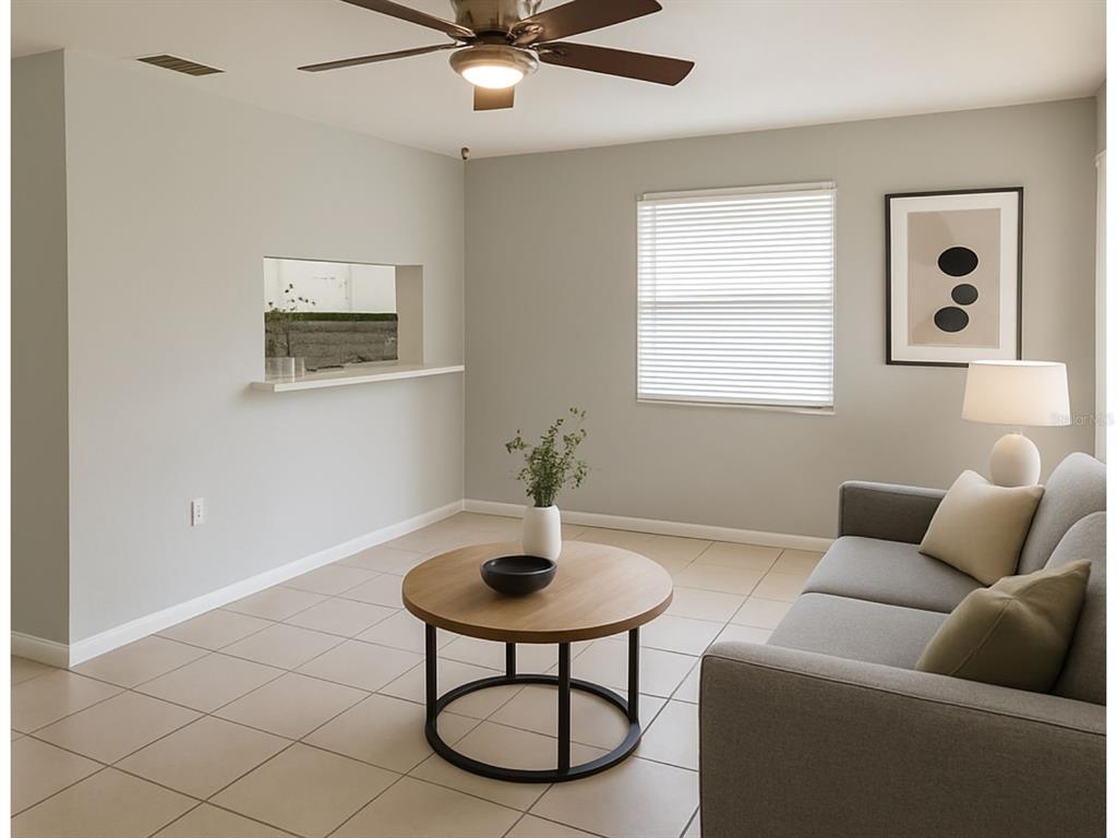A living room with light tile floors, a grey sofa, and a pass-through window — 2359/2361 CHESTNUT HILLS DRIVE, LAKELAND, FL