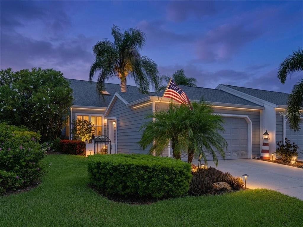 A gray house with a palm tree, American flag, and lighthouse decor at dusk — 1240 SPOONBILL LANDINGS CIRCLE, BRADENTON, FL