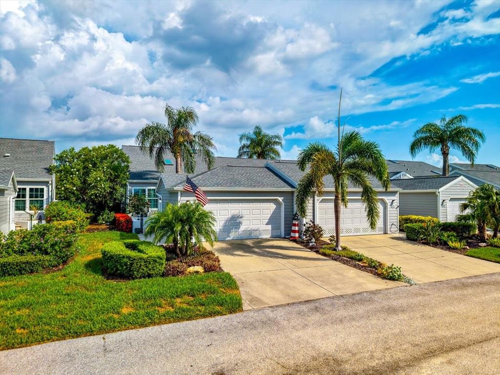 A single-story house with a gray roof, two garage doors, and palm trees in front — 1240 SPOONBILL LANDINGS CIRCLE, BRADENTON, FL