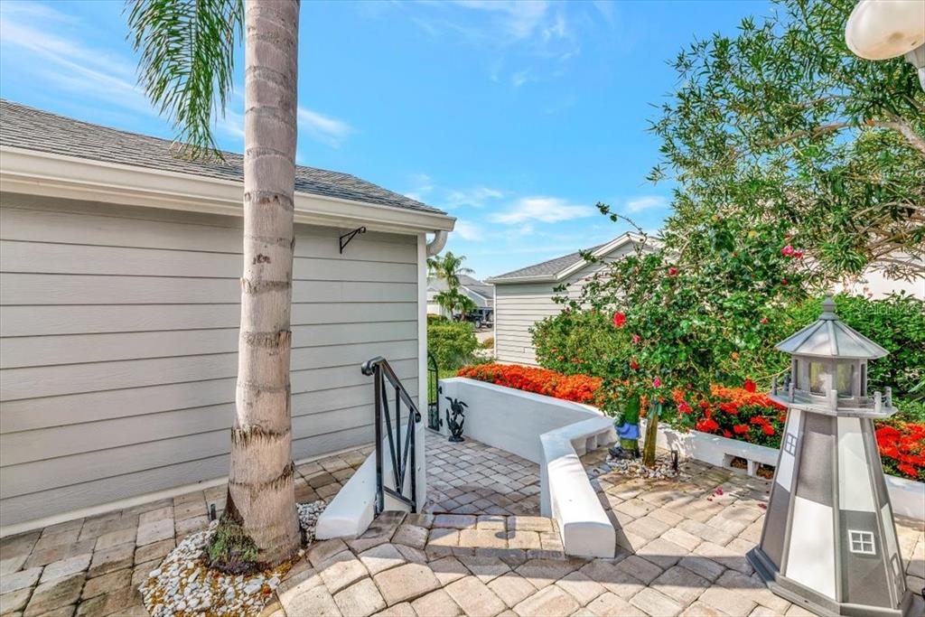 A paved walkway leads between two houses past a palm tree and a decorative lighthouse — 1240 SPOONBILL LANDINGS CIRCLE, BRADENTON, FL