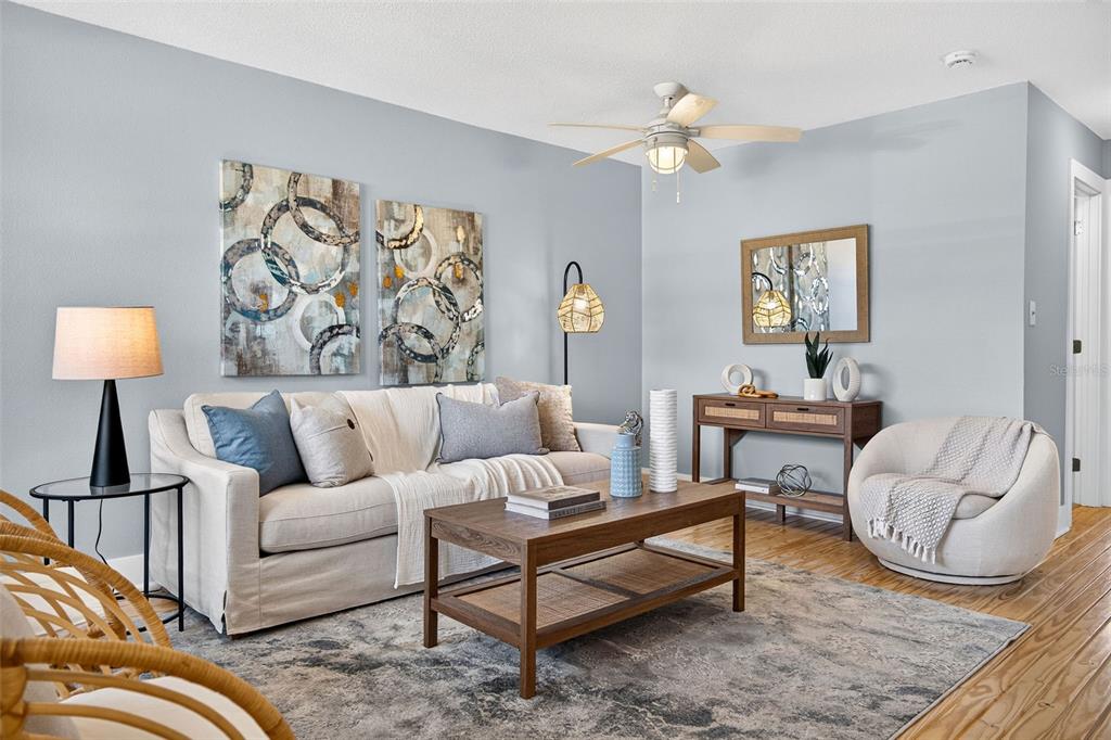 A living room features a beige sofa, wooden coffee table, and light blue walls — 2 CAUSEWAY BOULEVARD UNIT 102, DUNEDIN, FL