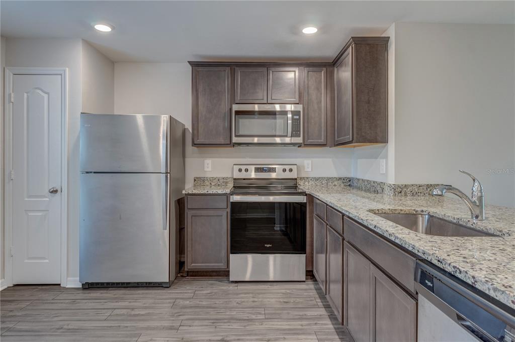 A kitchen features dark wood cabinets, stainless steel appliances, and speckled granite countertops — 4127 SNOWDROP STREET, NORTH PORT, FL