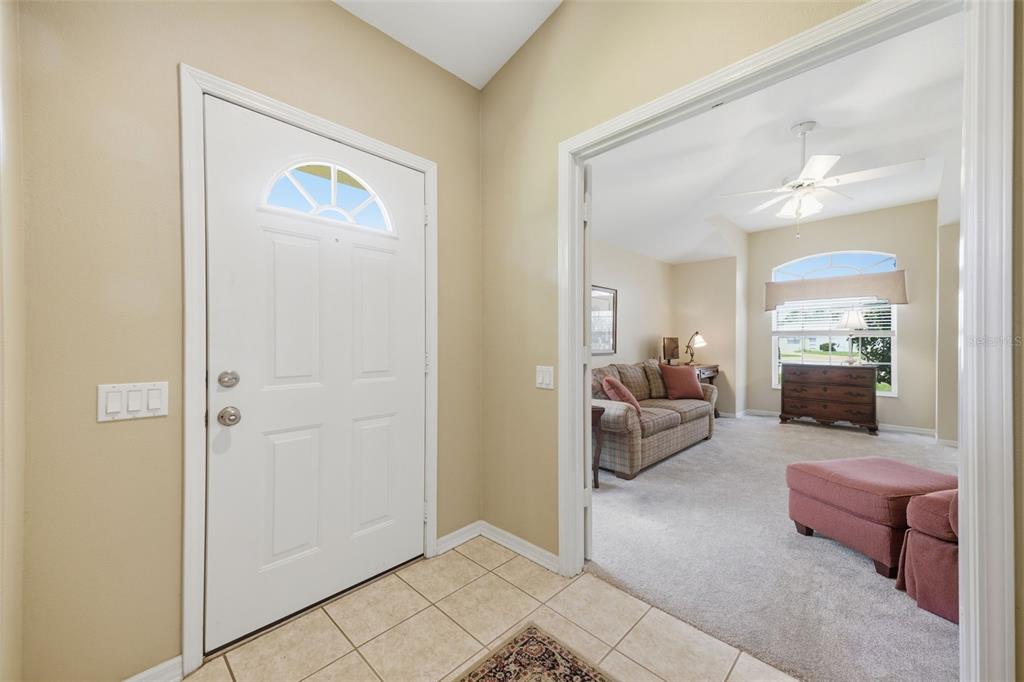 A tiled entryway leads into a carpeted living room with a sofa and ceiling fan — 5600 SIR BARTON COURT, WESLEY CHAPEL, FL