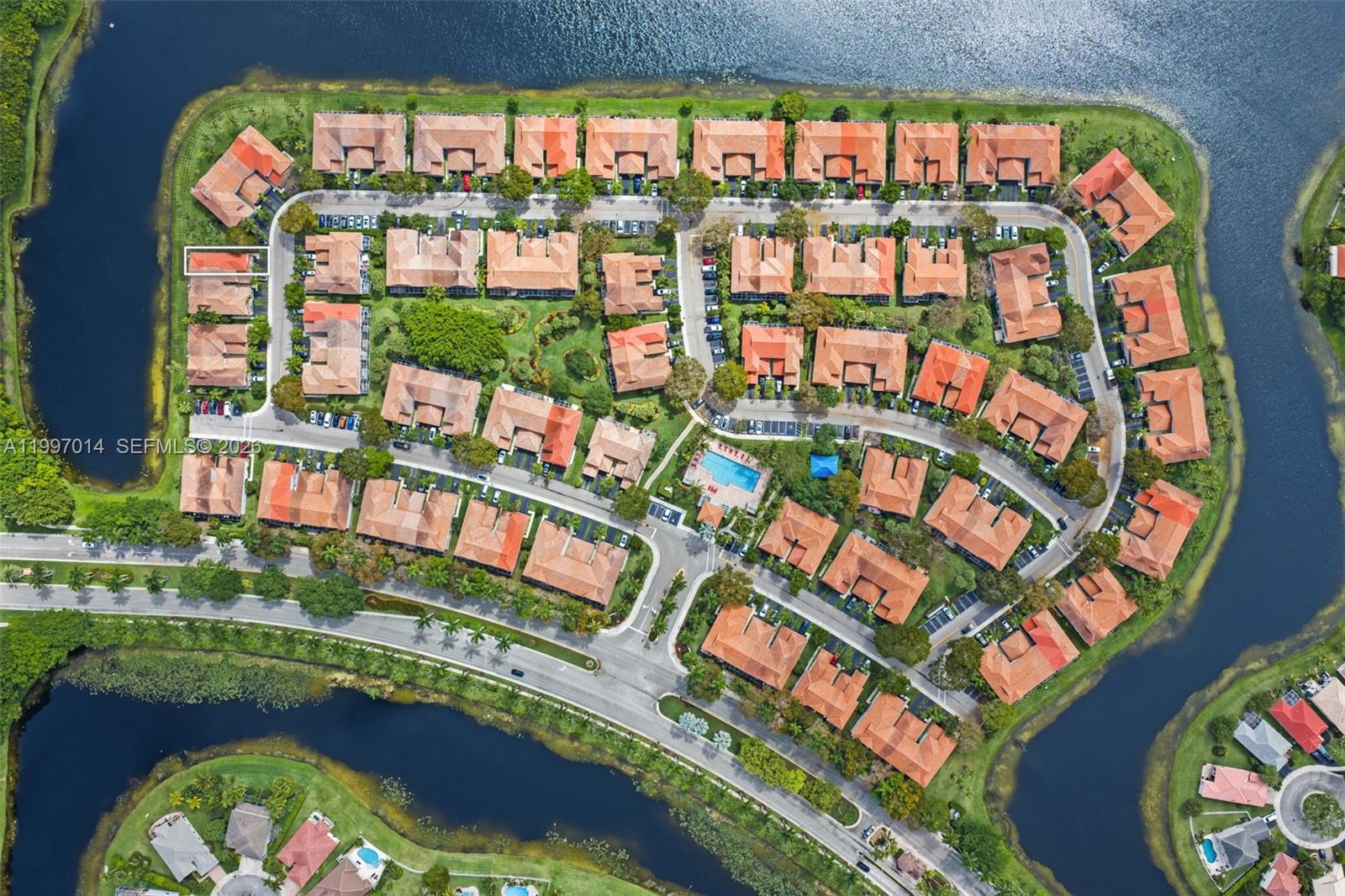 This aerial view shows a residential community with multiple townhomes, a swimming pool, and lakes — 3676 San Simeon Cir, Weston FL 33331, WESTON, FL