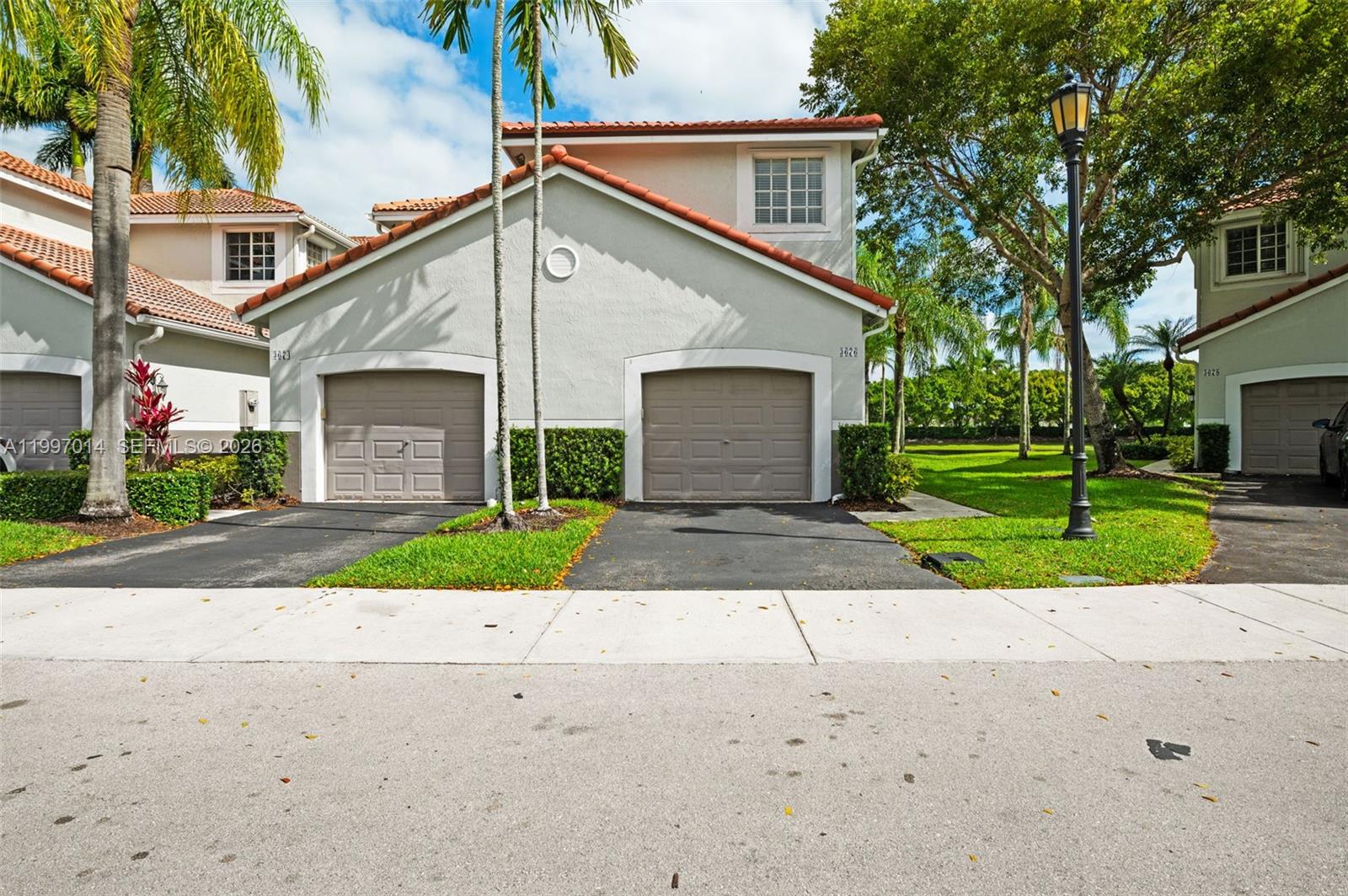A two-story townhouse exterior features two garage doors, a tile roof, and palm trees — 3676 San Simeon Cir, Weston FL 33331, WESTON, FL