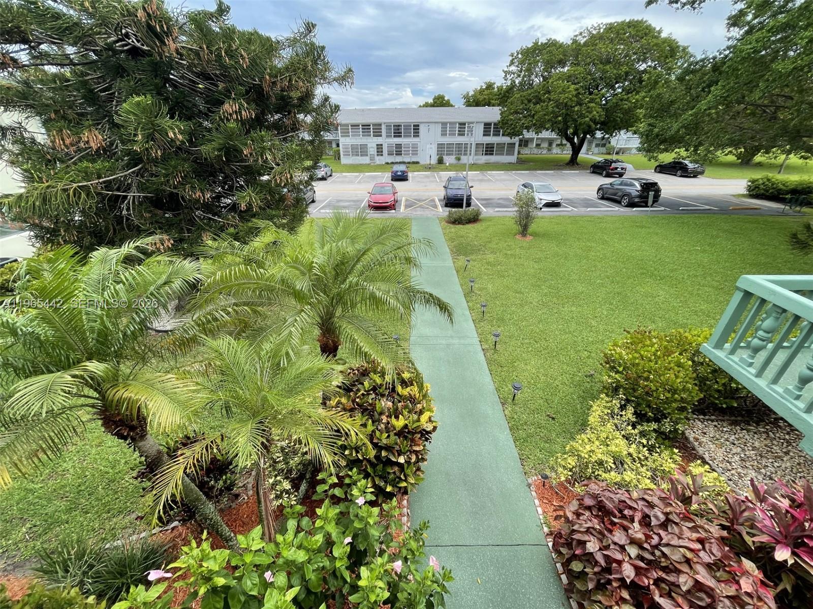 An elevated view shows a green walkway leading toward a parking lot and apartment building — 118 Upminster  E # 118, Deerfield Beach FL 33442, DEERFIELD BEACH, FL