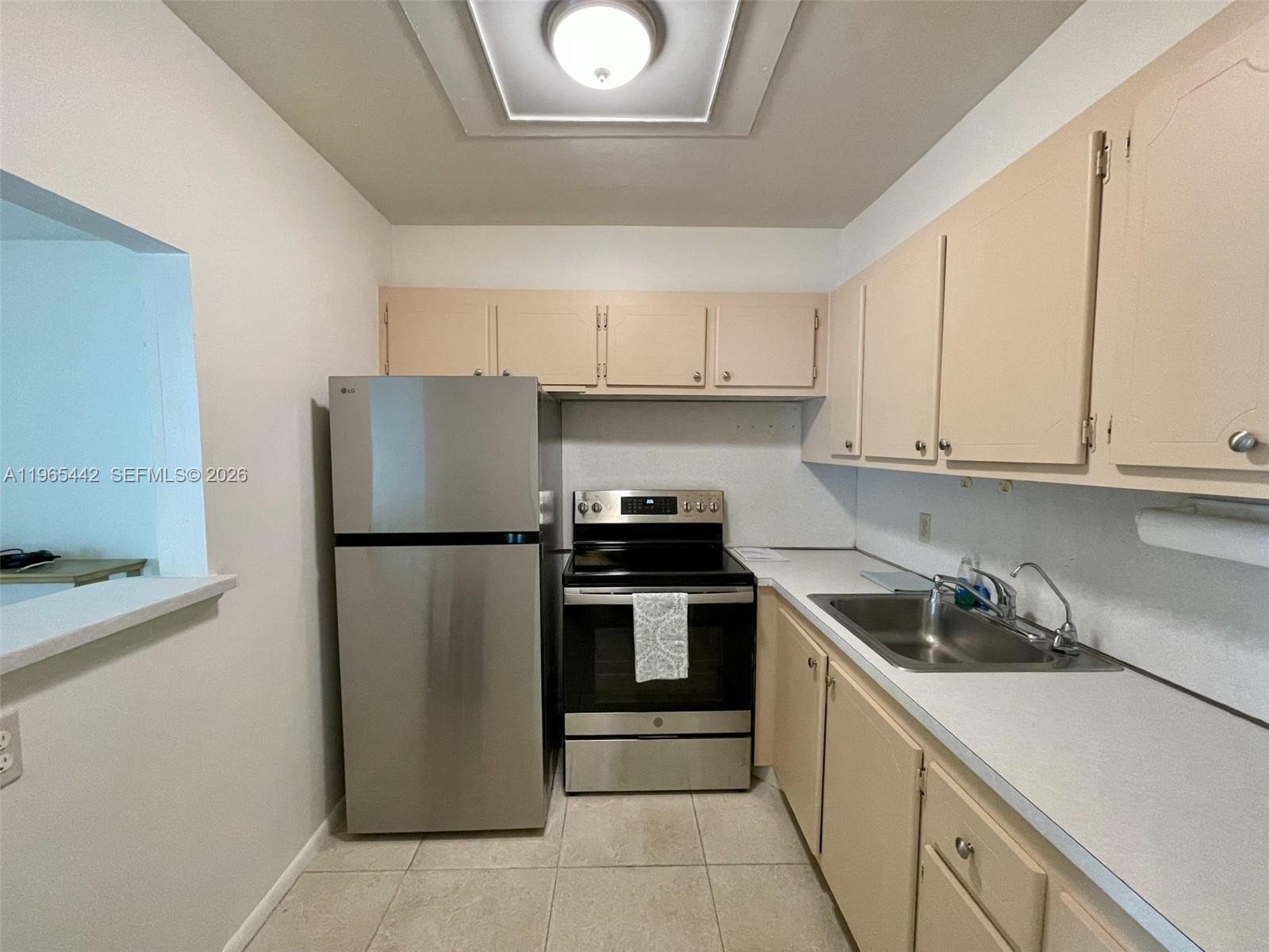 A kitchen features stainless steel appliances, light-colored cabinets, white countertops, and tiled flooring — 118 Upminster  E # 118, Deerfield Beach FL 33442, DEERFIELD BEACH, FL