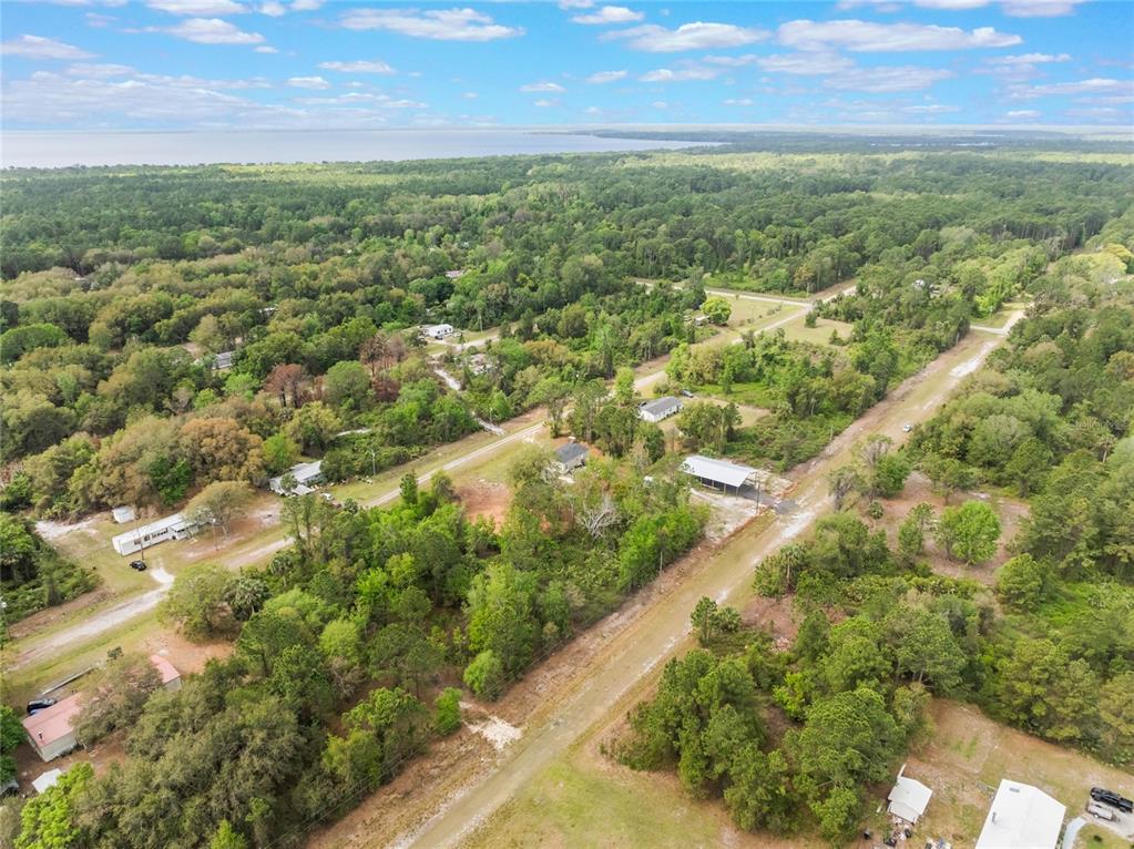 An aerial view shows a rural residential area with scattered houses, dirt roads, and dense trees — 515 GARDENIA AVENUE, GEORGETOWN, FL