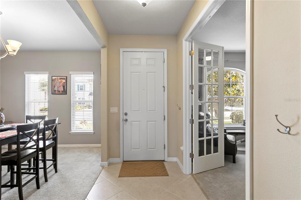 A foyer with tile flooring leads to a front door, a dining area, and French doors — 11412 LAKE LUCAYA DRIVE, RIVERVIEW, FL