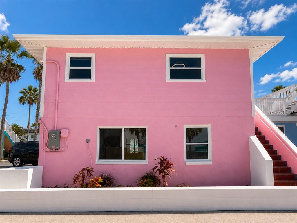 A two-story pink building with a white roof, exterior staircase, and a low concrete wall — 12609 SUNSHINE LANE, TREASURE ISLAND, FL