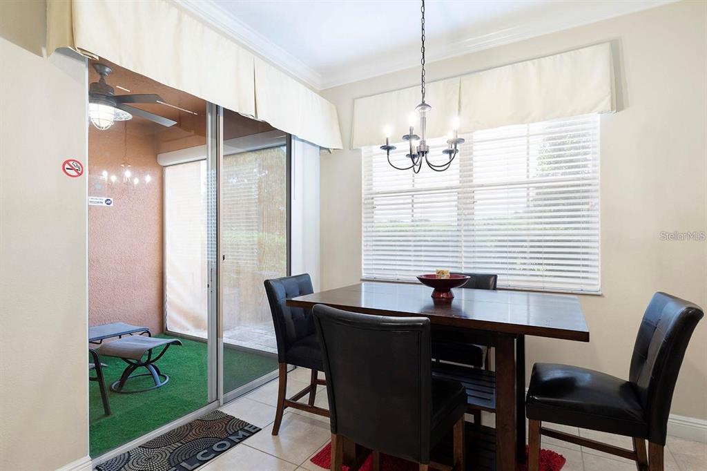 A dining area features a dark wood table, four black chairs, and a sliding glass door — 7596 ASSEMBLY LANE, KISSIMMEE, FL
