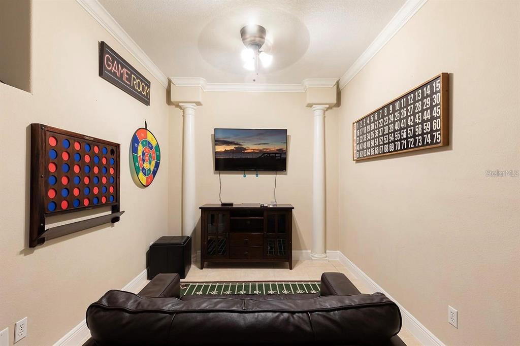 A game room features a wall-mounted Connect Four game, a dartboard, a television, and a sofa — 7596 ASSEMBLY LANE, KISSIMMEE, FL