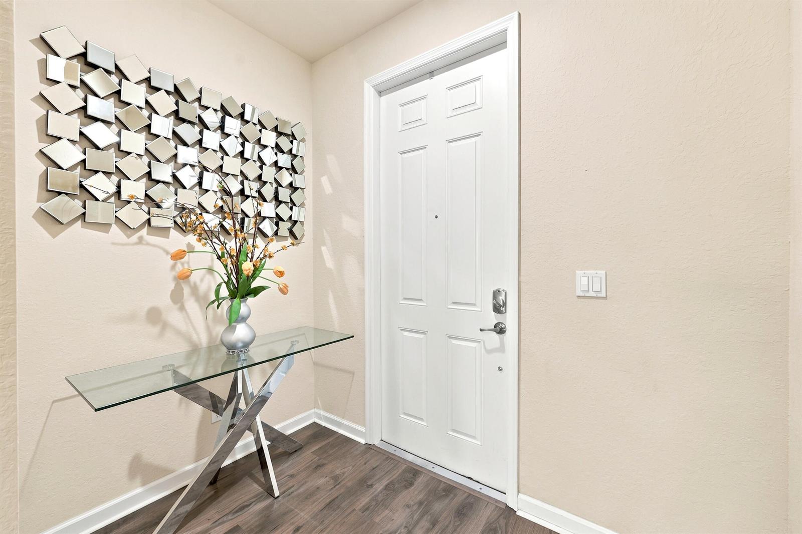 An entryway features a glass console table, a decorative mirror wall, and a white door — 4310 Chalmers Lane, West Palm Beach FL 33417, WEST PALM BEACH, FL