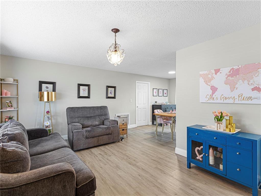 A living room features gray sofas, a blue console table, and light wood-look flooring — 3124 LECANTO STREET, HOLIDAY, FL