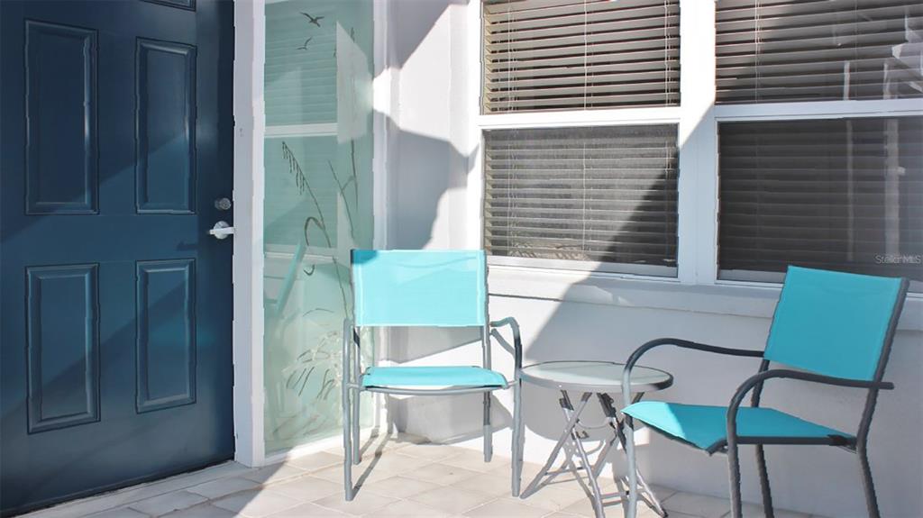 A patio features two teal chairs and a small table next to a blue door — 1241 SIESTA BAYSIDE DRIVE UNIT 1241-A, SARASOTA, FL