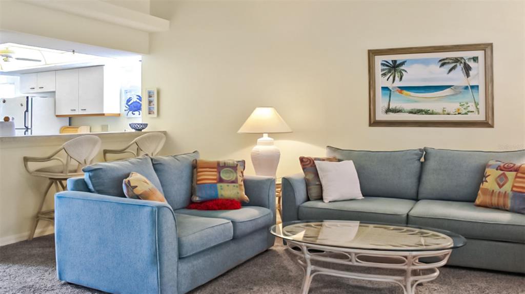 A living room features two blue sofas, a glass coffee table, and a kitchen pass-through — 1241 SIESTA BAYSIDE DRIVE UNIT 1241-A, SARASOTA, FL