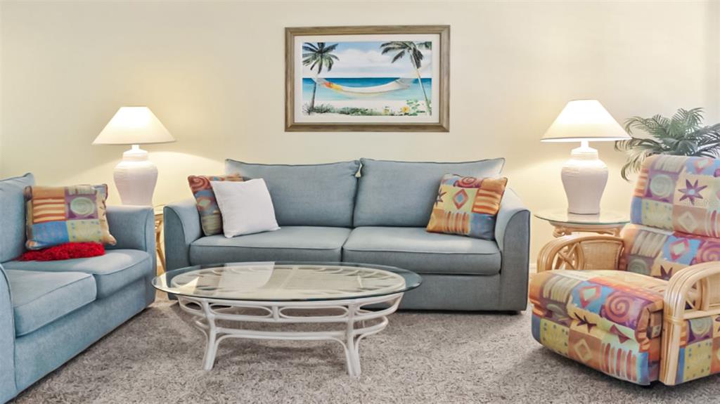 A living room features a blue sofa, a patterned armchair, and a glass-topped coffee table — 1241 SIESTA BAYSIDE DRIVE UNIT 1241-A, SARASOTA, FL