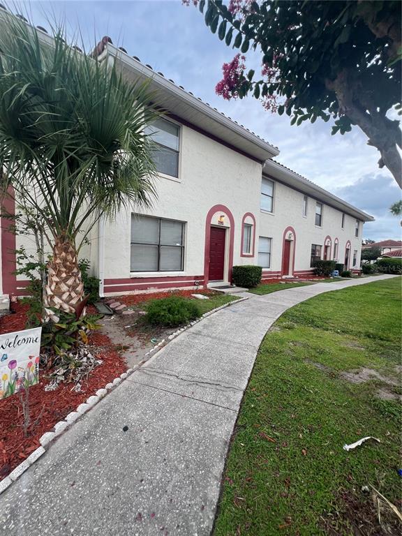 A two-story apartment building exterior features stucco walls, red trim, and a concrete walkway — 6231 YORKTOWN DRIVE UNIT 140, ORLANDO, FL
