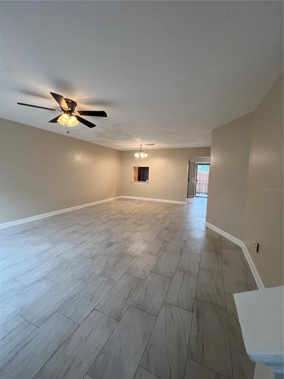 An empty room features light-colored wood-look tile flooring, a ceiling fan, and neutral walls — 6231 YORKTOWN DRIVE UNIT 140, ORLANDO, FL
