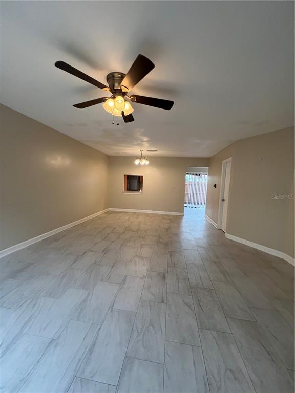 A living room with light-colored tile flooring, a ceiling fan, and a small wall cutout — 6231 YORKTOWN DRIVE UNIT 140, ORLANDO, FL