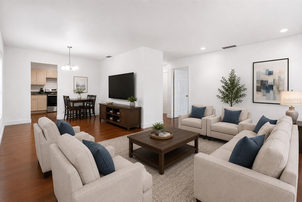 An open living area features dark hardwood flooring, white walls, and a central television stand — 1700 NEEDLEWOOD LANE, ORLANDO, FL