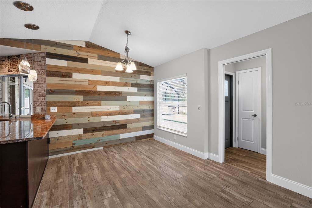 A dining area features a wood-plank accent wall, light gray walls, and wood-look tile flooring — 12421 WINDSWEPT AVENUE, RIVERVIEW, FL