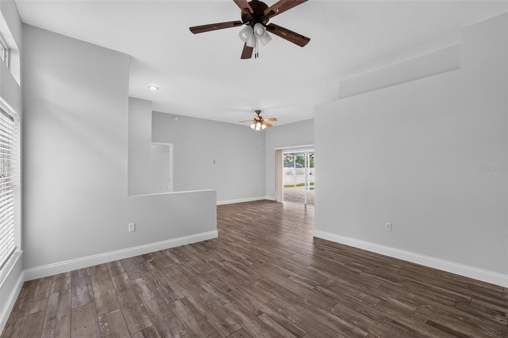 An open-concept living area features light gray walls, wood-look tile flooring, and two ceiling fans — 12421 WINDSWEPT AVENUE, RIVERVIEW, FL