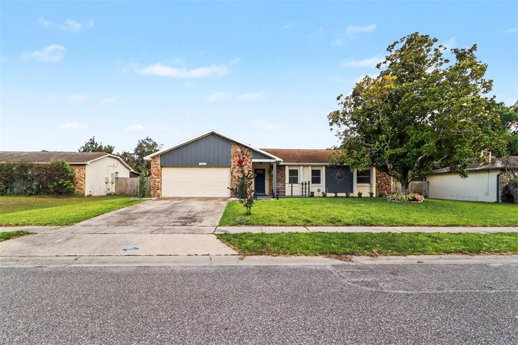 A single-story house with a two-car garage, stone accents, and a large tree in front — 3641 HAWTHORNE LANE, WINTER PARK, FL