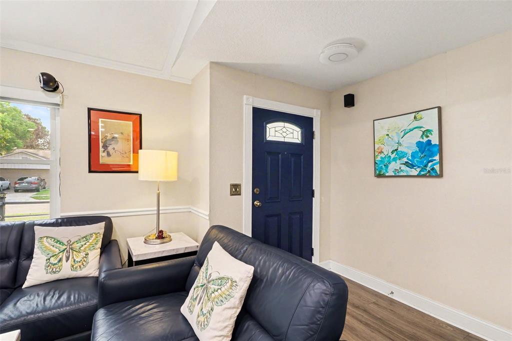 A living room features a dark blue front door, dark leather furniture, and butterfly-themed pillows — 3641 HAWTHORNE LANE, WINTER PARK, FL