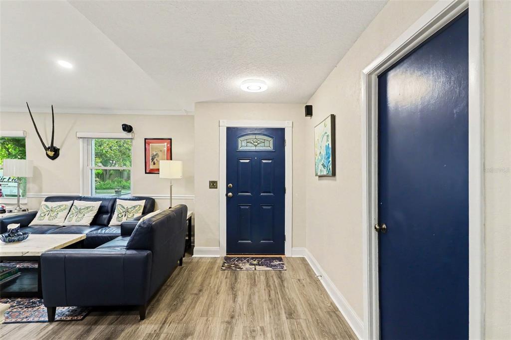 A living room with wood-look flooring, a blue sofa, and a blue front door — 3641 HAWTHORNE LANE, WINTER PARK, FL