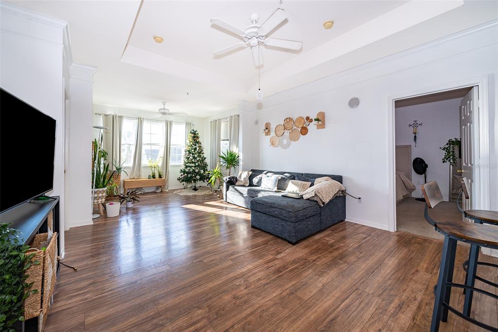 A living room features wood-look flooring, a sectional sofa, a ceiling fan, and a Christmas tree — 6413 ASTOR VILLAGE AVENUE UNIT 305, ORLANDO, FL