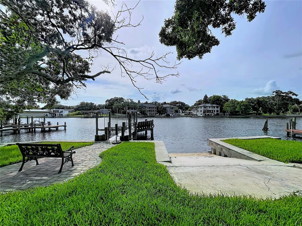 A waterfront view featuring a stone patio, a bench, a boat dock, and a boat ramp — 3312 N PERRY AVENUE, TAMPA, FL