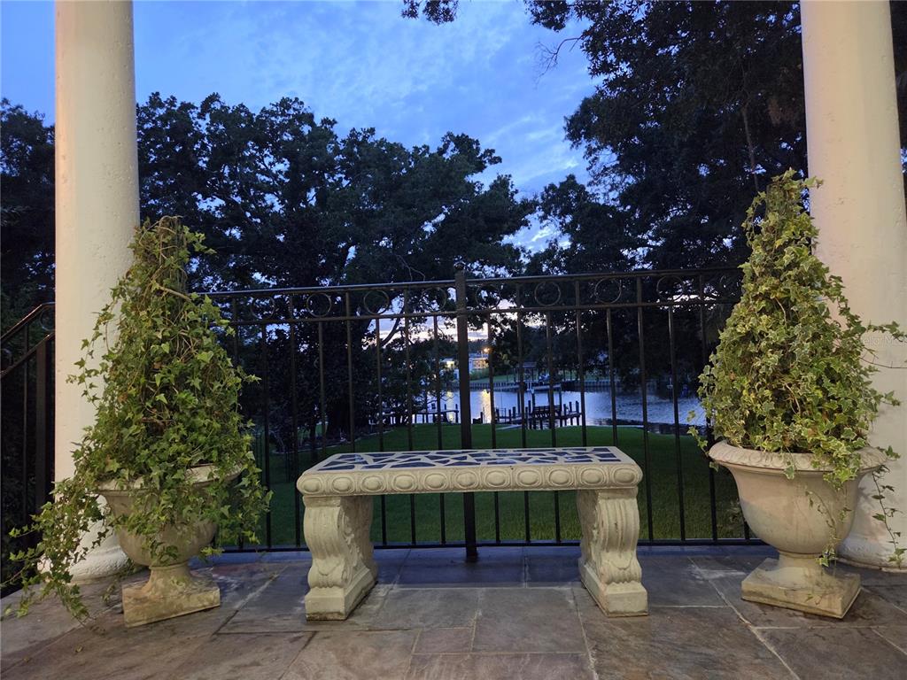 A stone bench sits on a patio between two potted ivy plants overlooking a lake — 3312 N PERRY AVENUE, TAMPA, FL