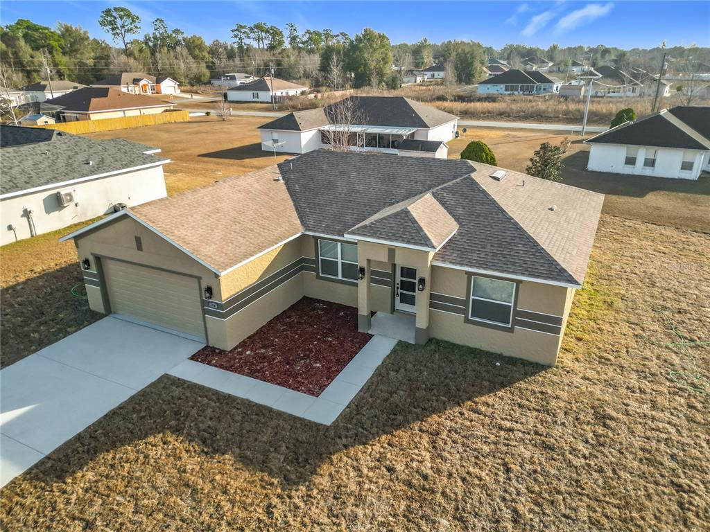 A modern kitchen features white cabinetry, a quartz-topped island, and stainless steel appliances — 12847 SW 73RD TERRACE, OCALA, FL
