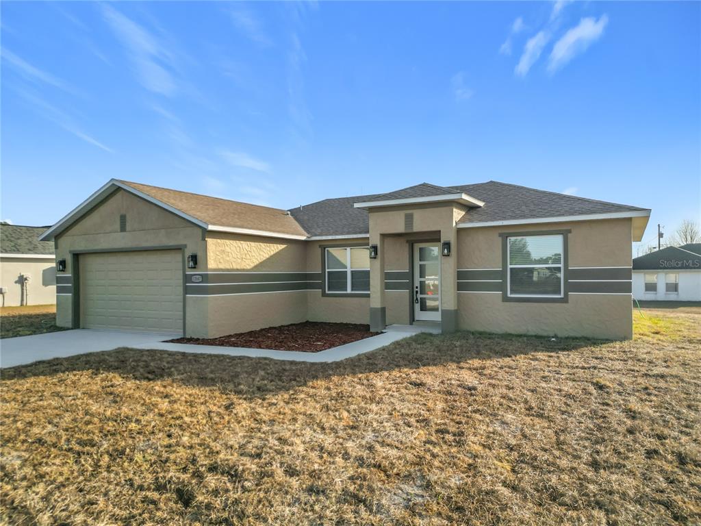 A kitchen features white cabinets, stainless steel appliances, and a gray tiled backsplash — 12847 SW 73RD TERRACE, OCALA, FL
