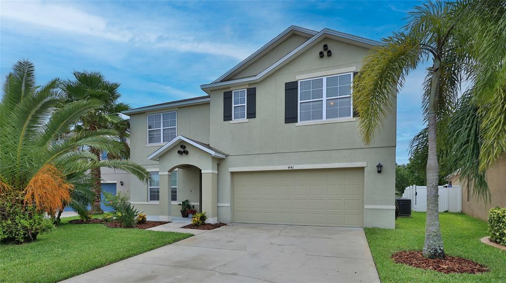 A two-story house with a beige stucco exterior, a two-car garage, and palm trees — 441 WHITE CORAL DRIVE, NEW SMYRNA BEACH, FL