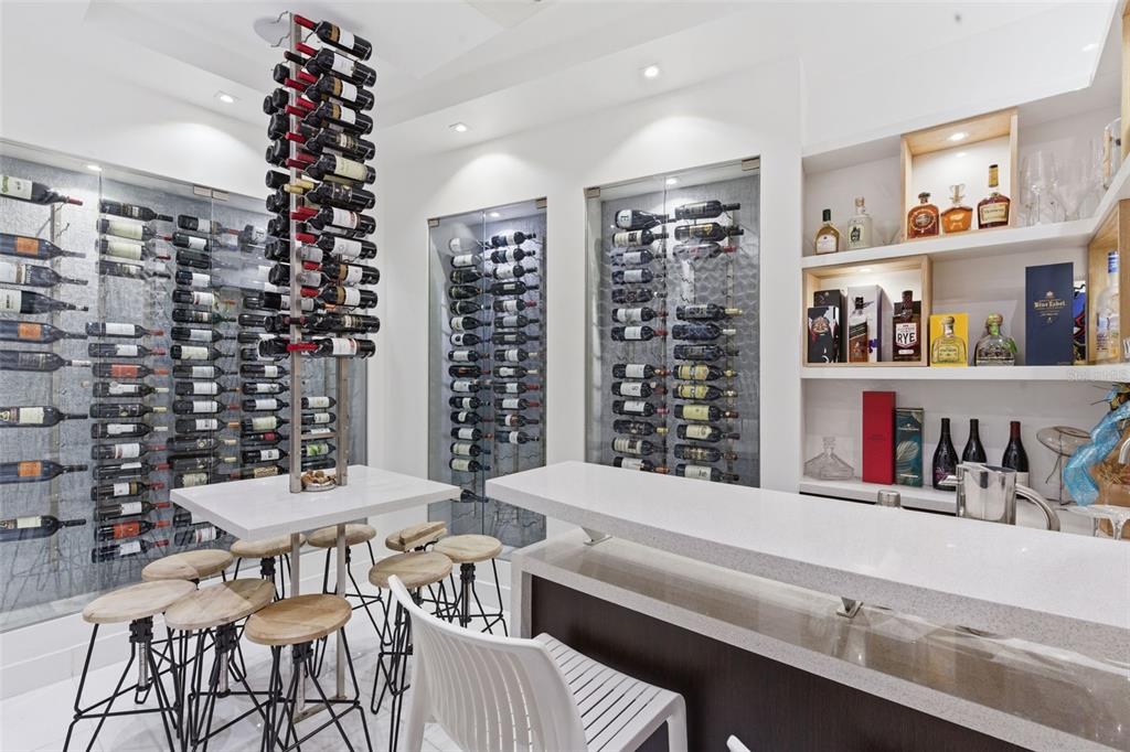 A modern home bar features a central wine rack, glass-enclosed wall storage, and white countertops — 57 QUINTAS DE SANTA MARIA II, MAYAGUEZ, PR