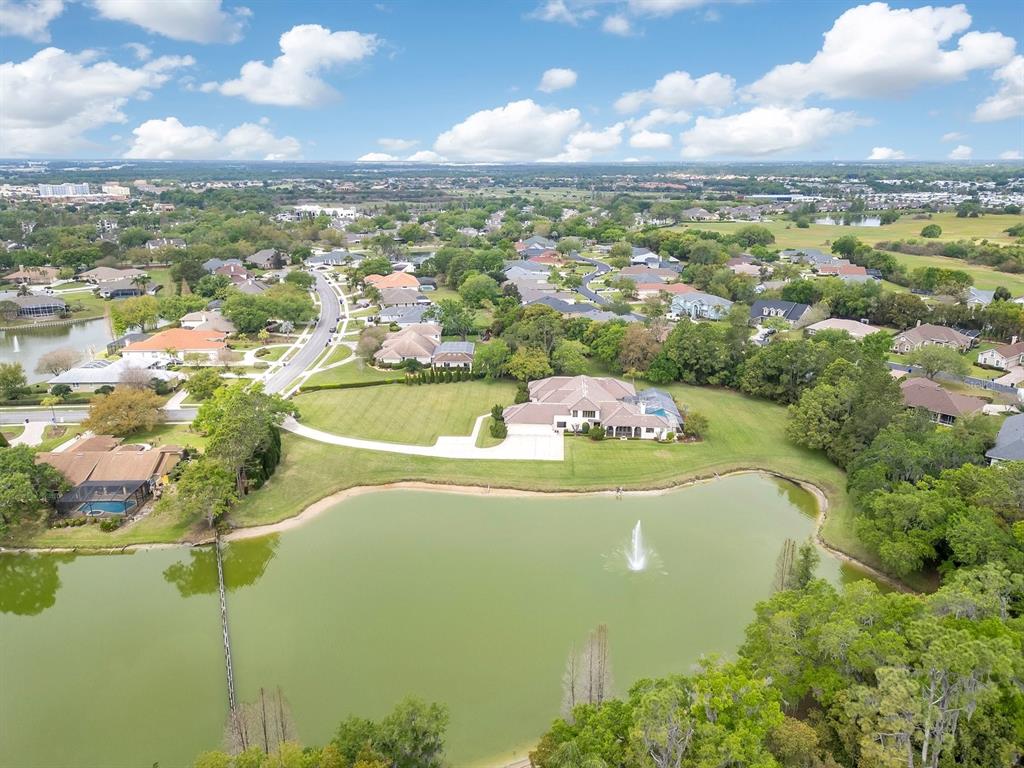 An aerial view shows a large house with a pool situated beside a pond — 3300 BRIDGEFIELD DRIVE, LAKELAND, FL