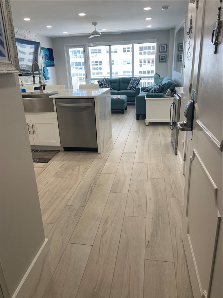 An open-concept living area features a kitchen with a stainless dishwasher and light wood flooring — 133 N Pompano Beach Boulevard # 507, Pompano Beach FL 33062, POMPANO BEACH, FL