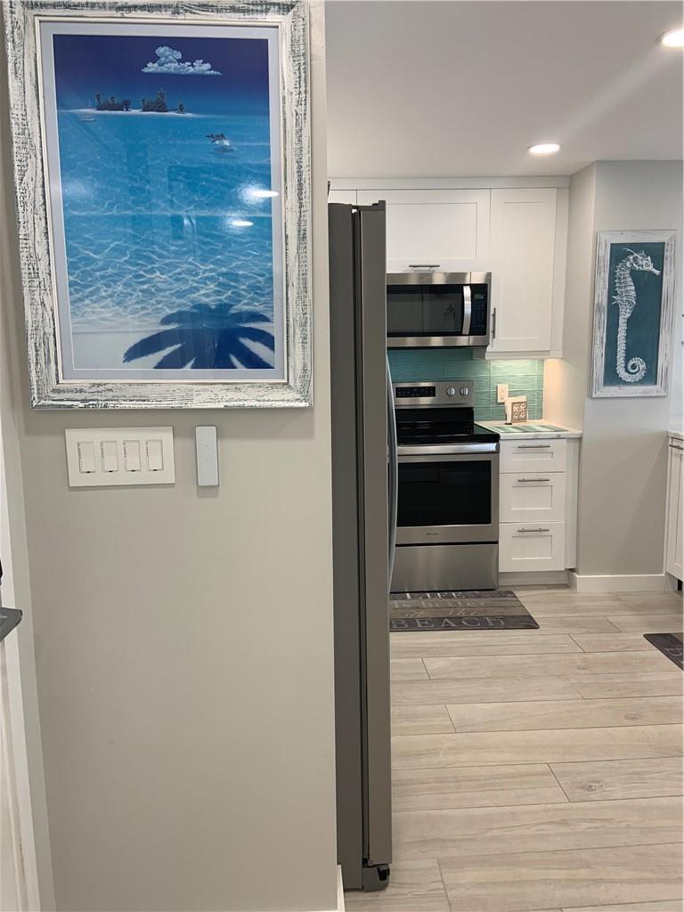A kitchen with white cabinets, stainless steel appliances, and a blue tiled backsplash — 133 N Pompano Beach Boulevard # 507, Pompano Beach FL 33062, POMPANO BEACH, FL
