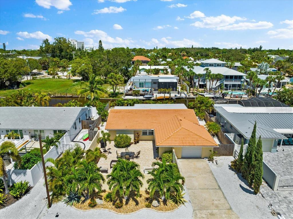 An aerial view shows a single-story house with a tiled roof, patio, and palm trees — 327 AVENIDA MILANO, SARASOTA, FL
