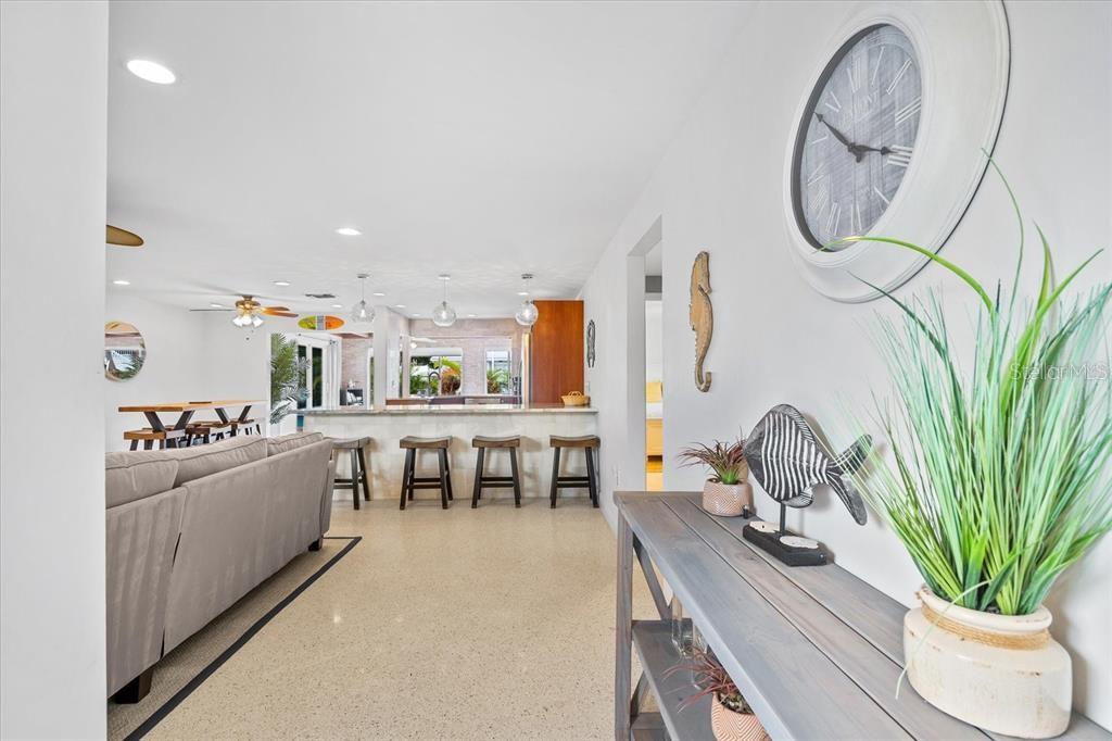 A view from a hallway looking into an open-concept living area with a kitchen bar — 327 AVENIDA MILANO, SARASOTA, FL
