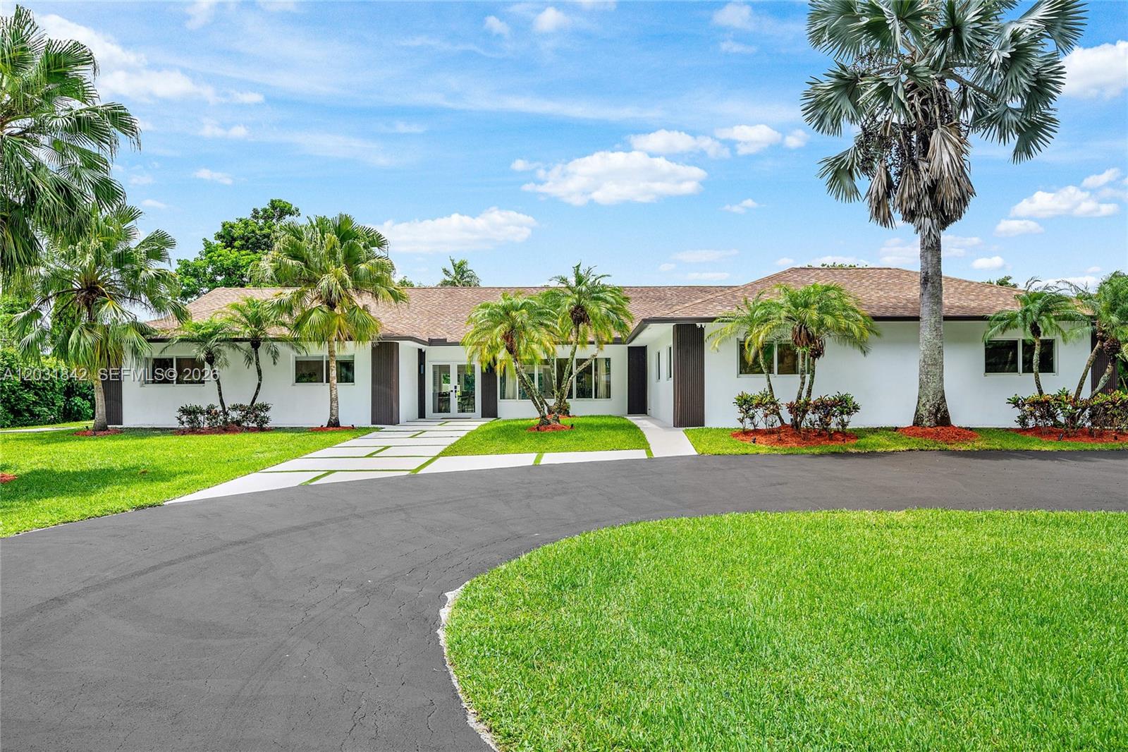 A modern single-story house exterior features a concrete paver walkway and palm trees at sunset — 13900 Mustang Trl, Southwest Ranches FL 33330, SOUTHWEST RANCHES, FL