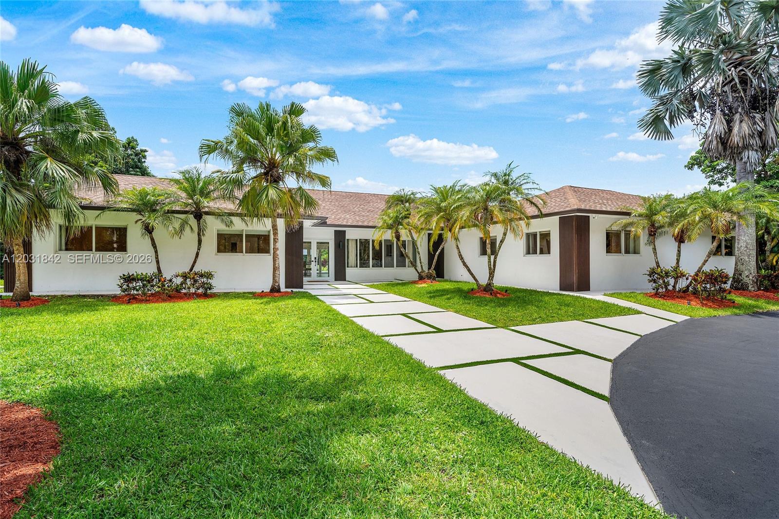 A single-story house with a white exterior, palm trees, and a paved driveway at dusk — 13900 Mustang Trl, Southwest Ranches FL 33330, SOUTHWEST RANCHES, FL