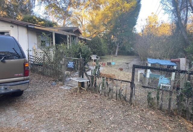 A brown SUV is parked next to a house with a fenced yard and playhouse — 15137 NE 141st Street, FL 32134, FL