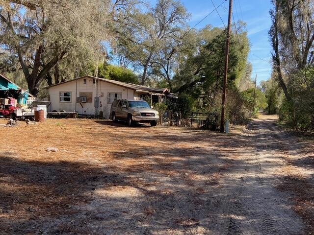 A light-colored house sits on a dirt lot with a parked SUV in front — 15137 NE 141st Street, FL 32134, FL